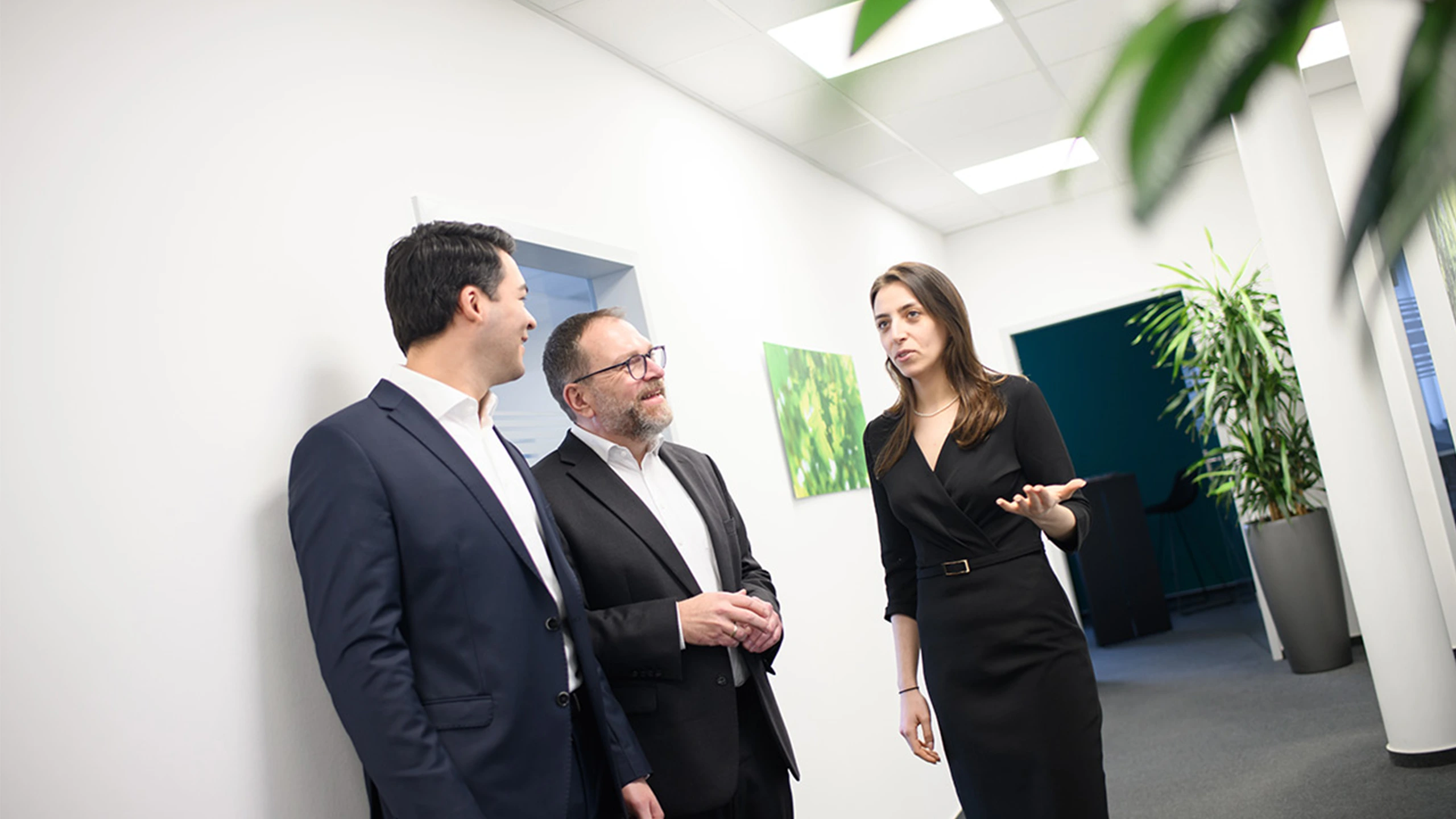 Drei Mitarbeitende vom Impact Investor Abacus Alpha stehen auf dem Flur des modernen, hellen Bürogebäudes.