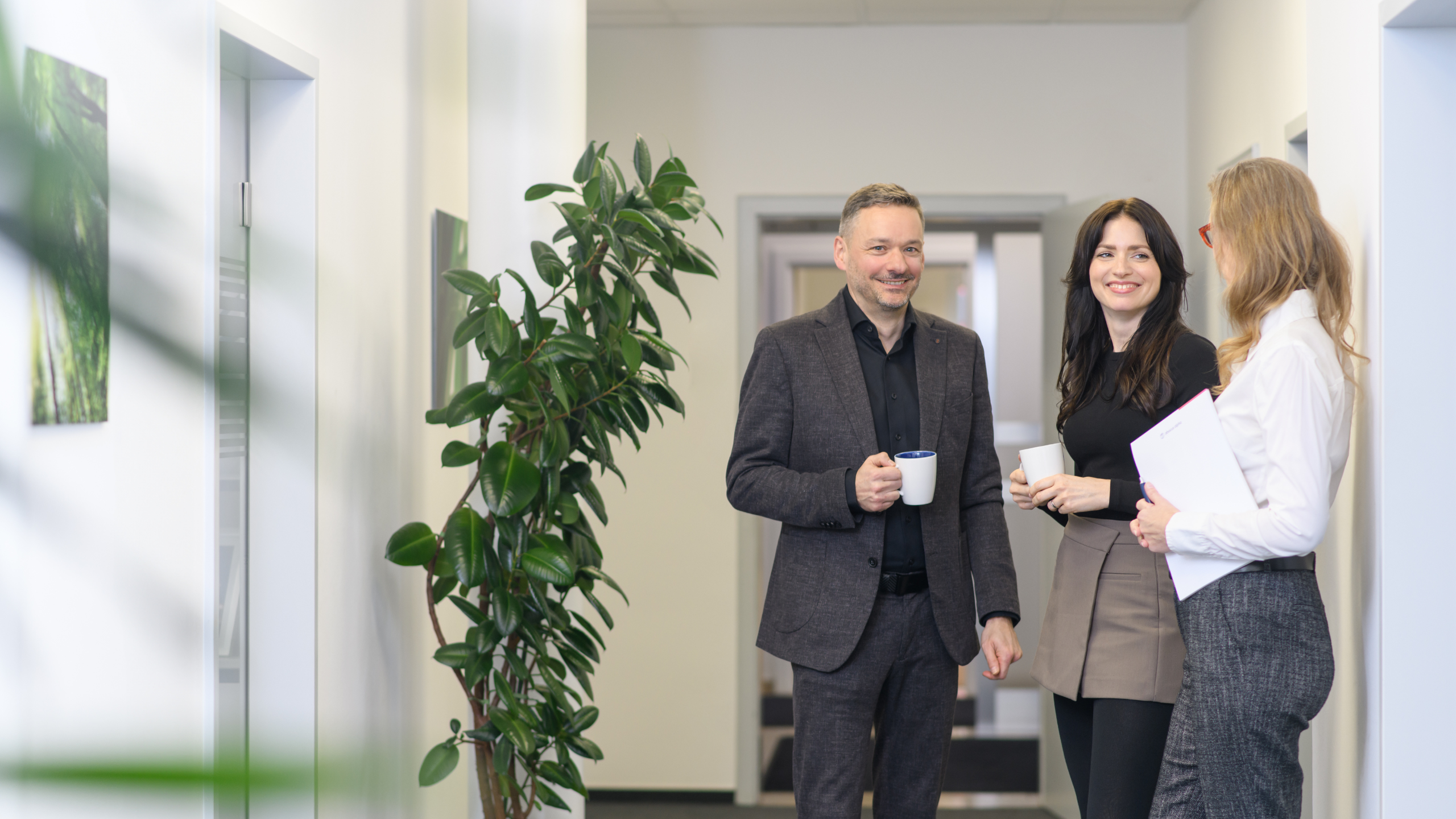 Unser Team bei Abacus alpha: Drei mitarbeitende stehen im Büroflur und unterhalten sich.