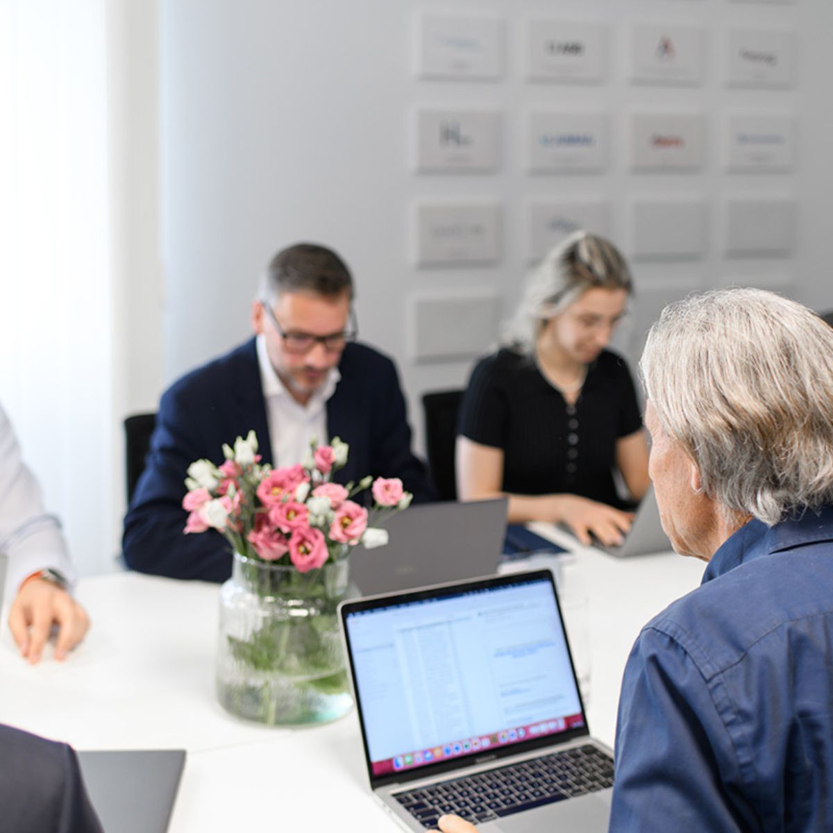 Symbolbild Karriere machen bei Impact Investor Abacus alpha: Team am Konferenztisch vor Laptops sitzend